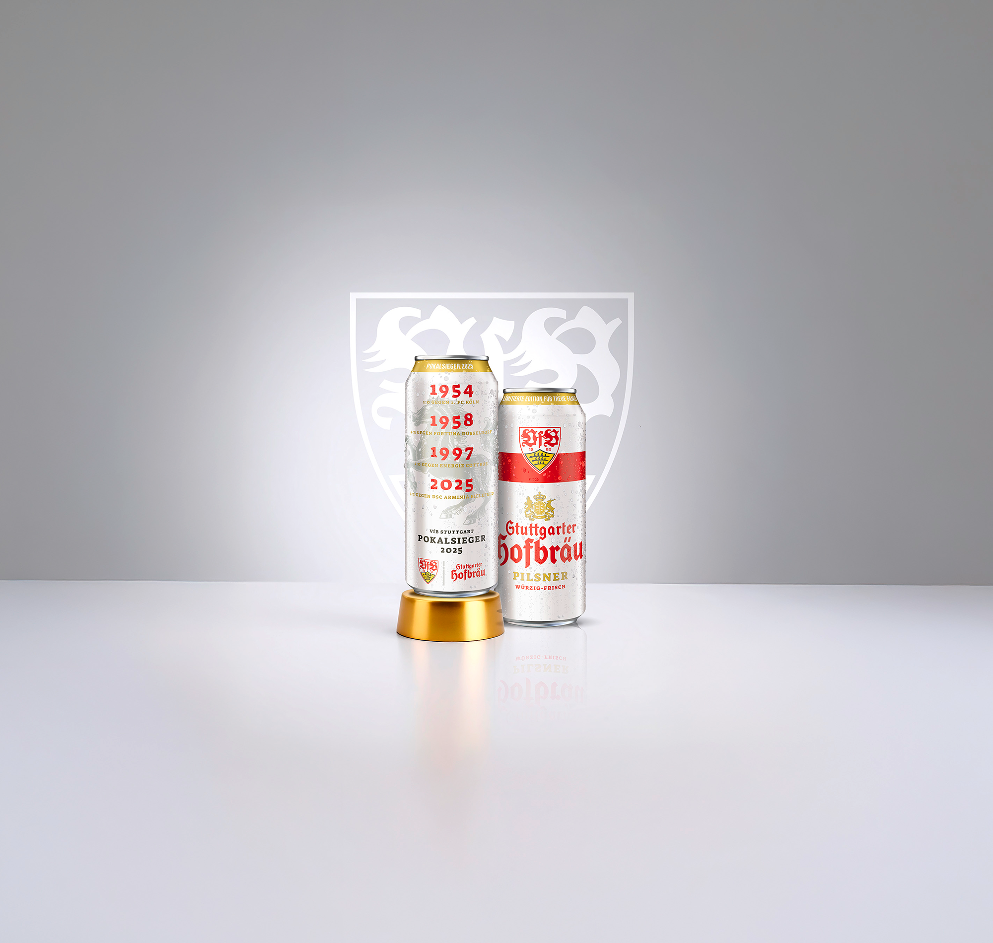Zwei Dosen Stuttgarter Hofbräu mit VfB-Stuttgart-Design stehen nebeneinander. Im Hintergrund ist ein weißes Wappen zu sehen.