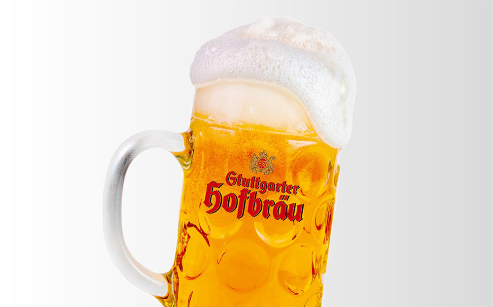 Ein voller Bierkrug mit Schaum steht vor einem weißen Hintergrund.