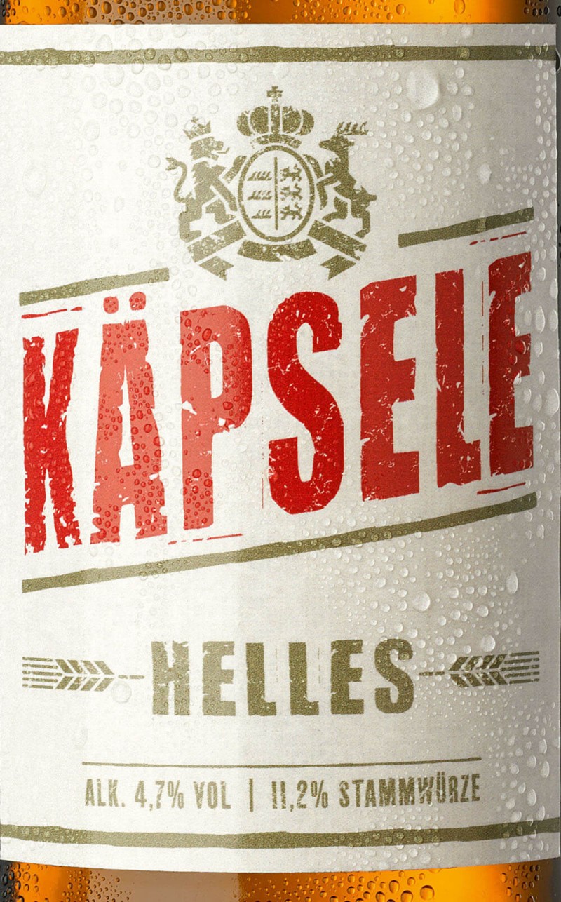 Nahaufnahme eines Bieretiketts mit dem Wort KAPSELE in roten Lettern, umgeben von Wassertröpfchen.