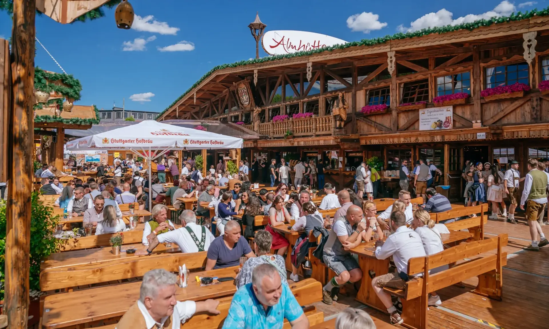Viele Menschen genießen Getränke und Gespräche in einem überfüllten Biergarten an einem sonnigen Tag.