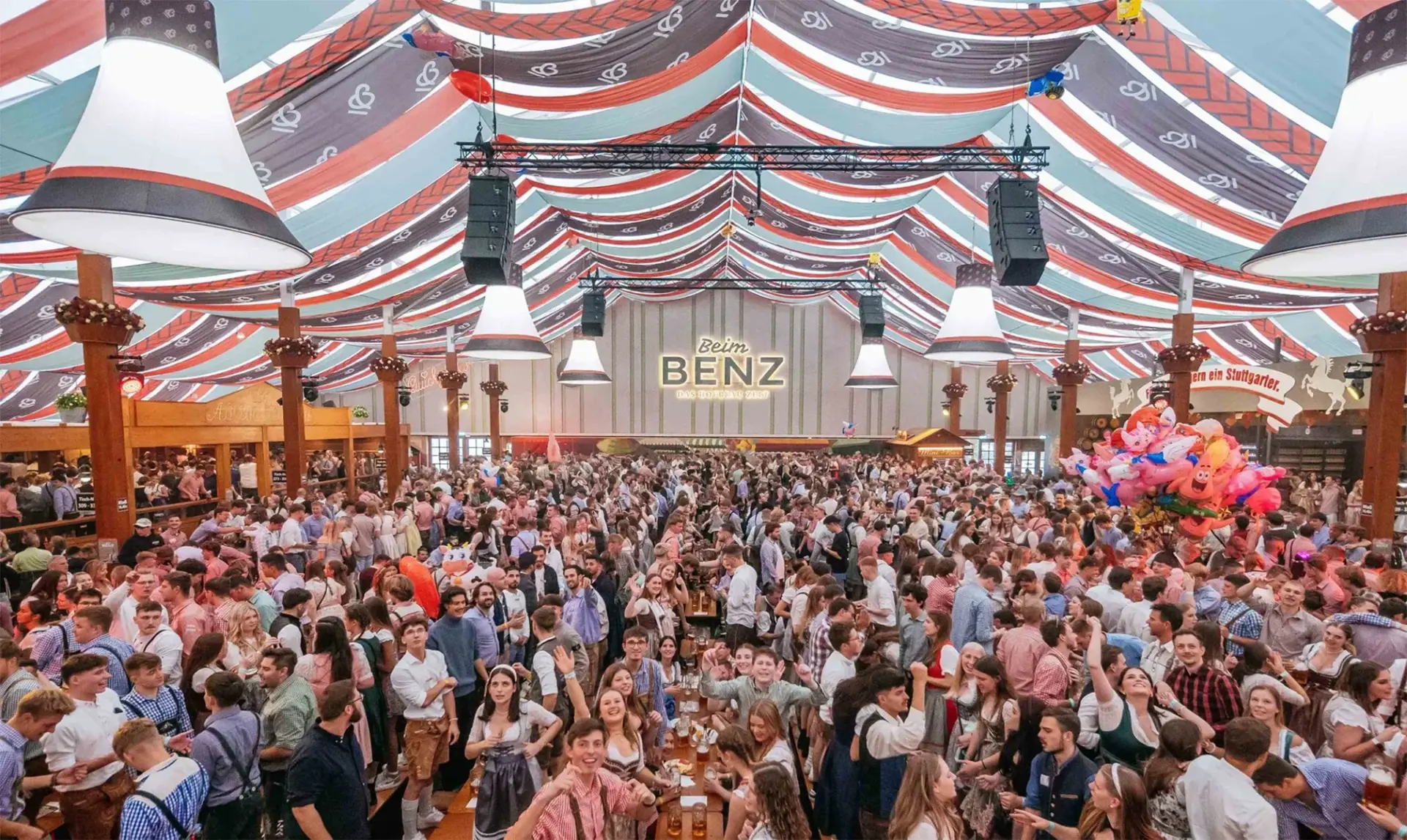 Großes Festzelt mit vielen Menschen in traditioneller Kleidung, die feiern.